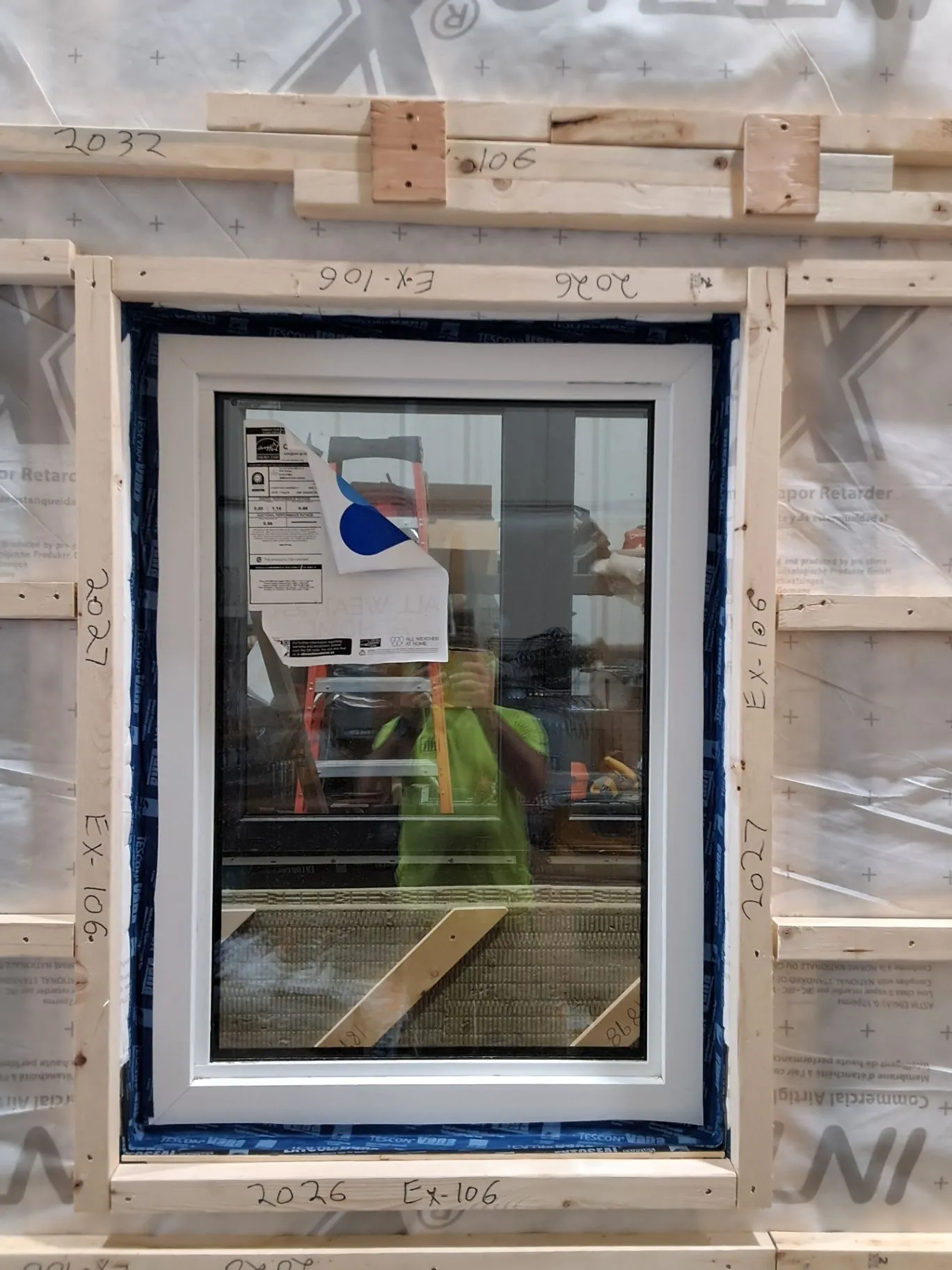 A white-framed window installed in a timber wall with insulation visible around it.